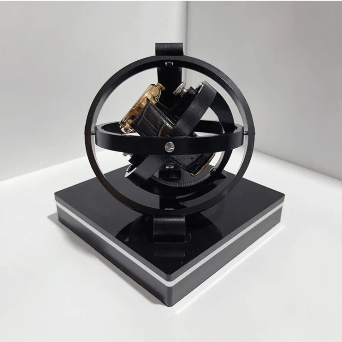 Fitlybuy luxury black spherical automatic watch winder holding a gold wristwatch on a square base against a white wall.