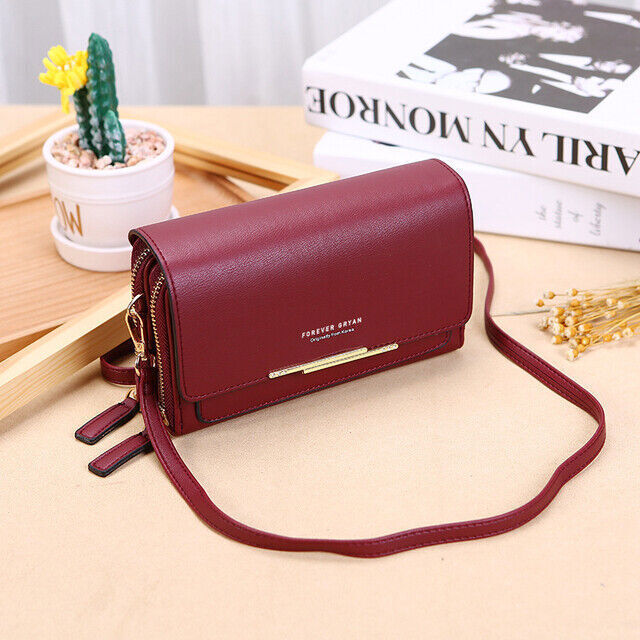 Fitlybuy burgundy leather crossbody bag with gold accents, side zippers, and strap, placed on a table with decor.