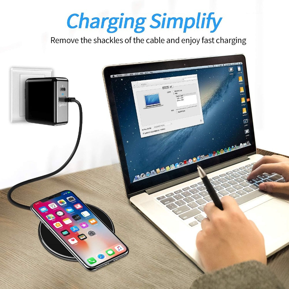 Black Fitlybuy 30W wireless charging pad powering an iPhone near a laptop on a wooden desk.